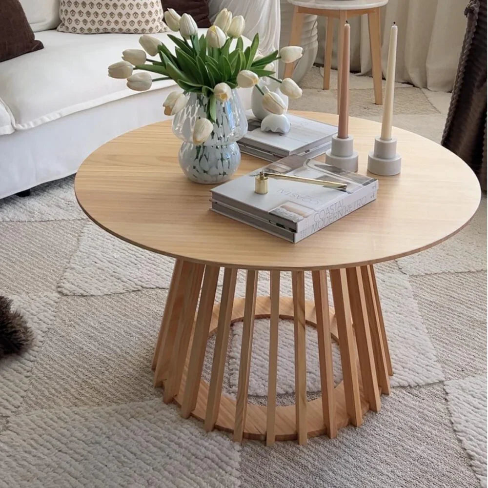 Round wooden coffee table with slatted base design, styled with books, candles, and a vase of tulips in a modern living room – Bar Stool Centre Australia.